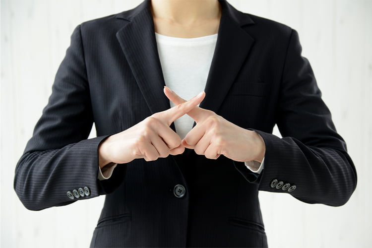 指でバツをつくる経理担当の女性